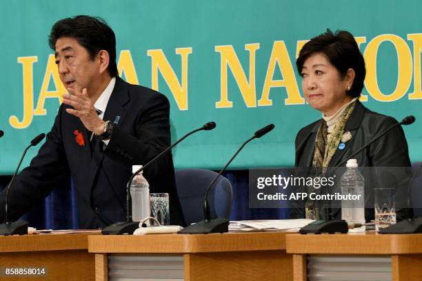 Japan's Prime Minister and President of ruling Liberal Democratic Party Shinzo Abe gestures as he answers questions beside Tokyo Governor and head of...