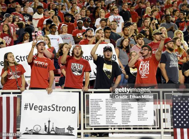 Fans cheer behind a #VegasStrong sign and a sign listing the 58 victims killed in Sunday's mass shooting before the team's game against the San Diego...