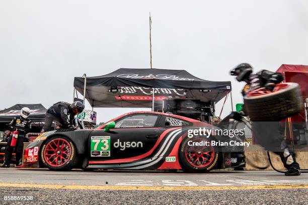 Crewmen service the Porsche 911 GT3 R of Patrick Lindsey, Joerg Bergmeister, of Germany, and Matthew McMurray during pit stop practice before the...