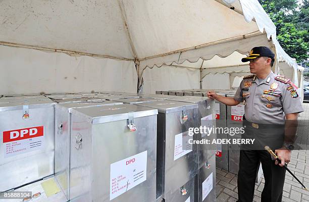 An Indonesian police officer inspects sealed ballot boxes at a subdistrict office in Jakarta on April 10 before a national tabulation which will...