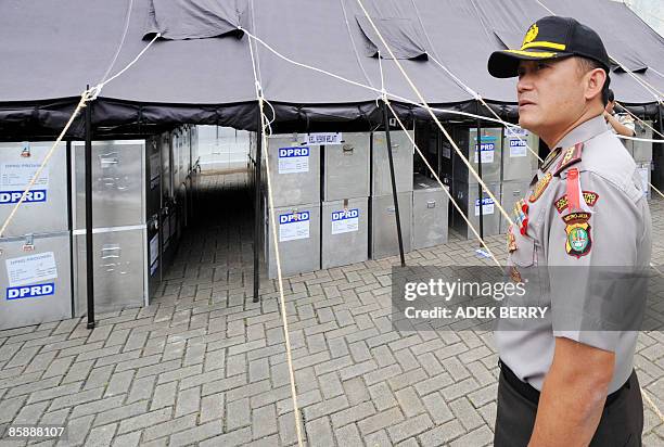 An Indonesian police officer inspects sealed ballot boxes at a subdistrict office in Jakarta on April 10 before a national tabulation which will...