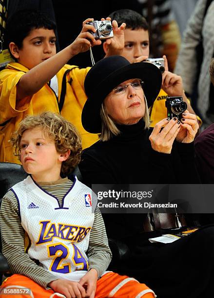 Actress Diane Keato with her son Duke looking on takes a picture of Kobe Bryant of the Los Angeles Lakers before the strat of the game against the...