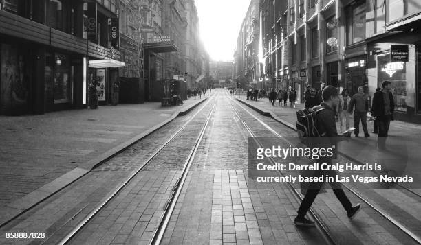 male shopper carrying bags walking across a street in downtown helsinki finland (black and white image) - zwart wit polaroids stockfoto's en -beelden