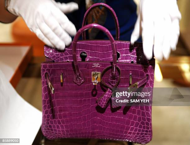 Woman inspects Hermes crocodile skin bag in Taipei on April 10, 2009. French luxury goods group Hermes hailed a Taiwan court's ruling to impose a...