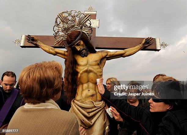 Worshippers touch a replica of the crucifix during the Santisimo Cristo del Salvador and el Amparo brotherhood procession at the playa Malvarrosa on...