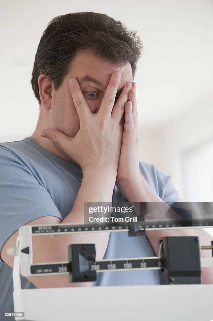 Man looking through hands at number on scale