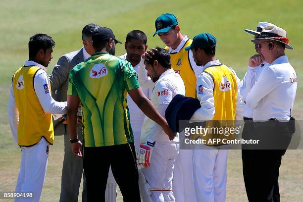 Bangladesh batsman Mushfiqur Rahim holds his head as he is attended by umpires, medics and team members after he was hit on the head by a ball...