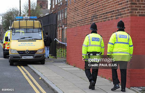 Police officers patrol the area around a house in Liverpool, north west England on April 10, 2009 following arrests and raids in Liverpool,...