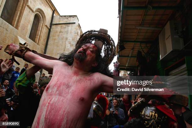 Christian pilgrims re-enact the Crucifixion of Jesus as they follow the path of his Passion through the narrow streets of the Old City on April 10,...