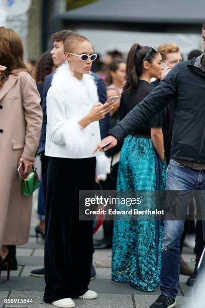 Guest wears white sunglasses, a white jacket with fur, black pants, and attends Le Defile L'Oreal Paris as part of Paris Fashion Week Womenswear...