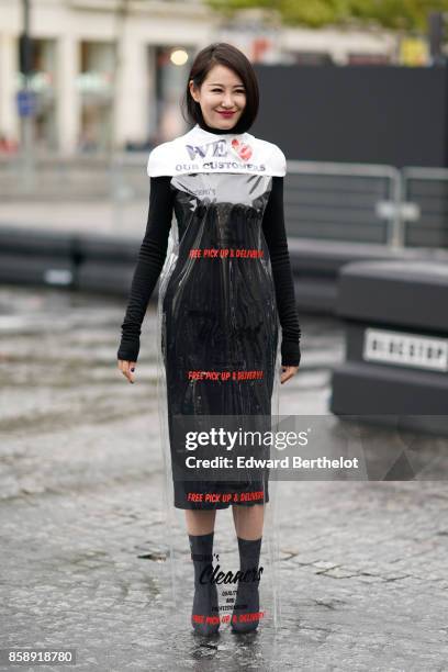 Zuo An Xiao wears a dress made of clear plastic, over a black dress with black sleeves, and attends Le Defile L'Oreal Paris as part of Paris Fashion...