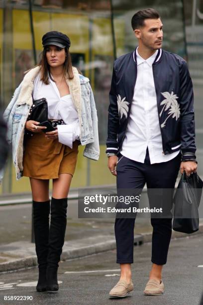 Guest wears a black beret hat, a denim jacket with fur, brown suede skirt, black boots ; a guest wears a blue bomber jacket, a white shirt, cropped...