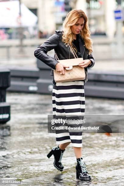 Guest wears a black leather jacket, a chanel bag, a striped skirt, black shoes and attends Le Defile L'Oreal Paris as part of Paris Fashion Week...