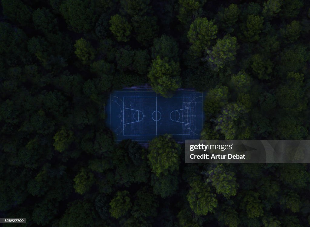 Aerial picture taking with drone of a stunning empty basketball court in the middle of the nature surrounded by the forest in visual and aesthetic picture taken from directly above view.