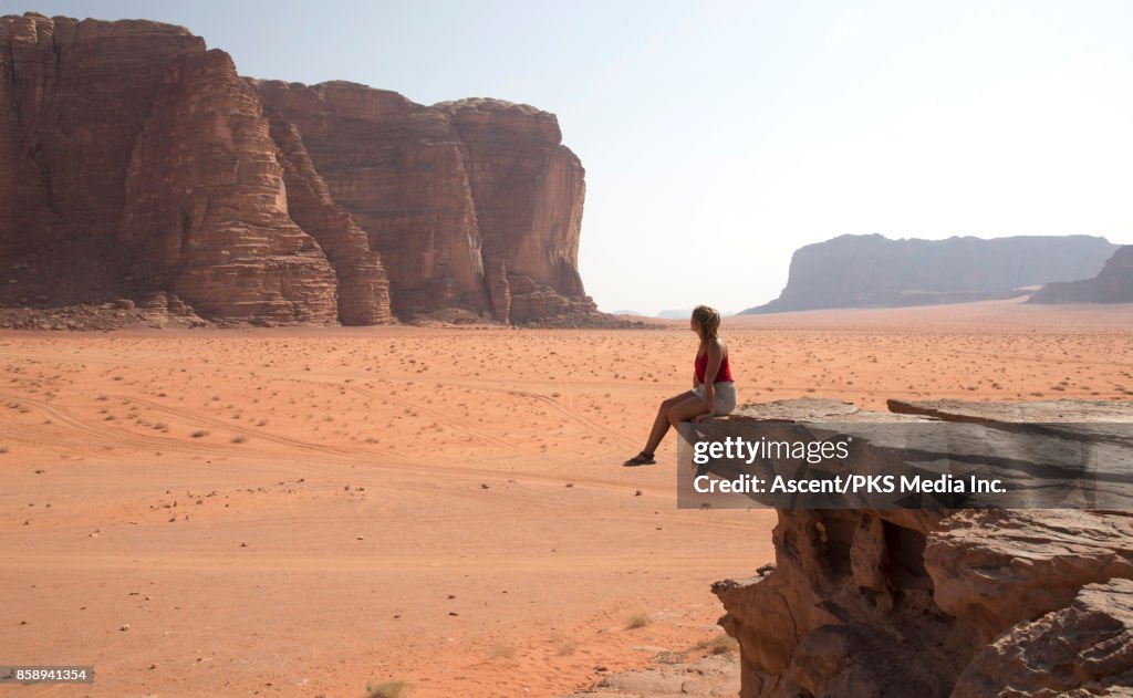 Young woman looks across desert landscape from raised viewpoint