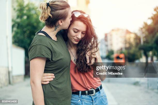 beautiful female couple embracing and kissing on the street - photos of lesbians kissing stock pictures, royalty-free photos & images