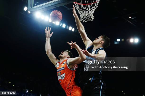 Cameron Gliddon of the Taipans forces up a shot against Rob Loe of the Breakers during the round one NBL match between the New Zealand Breakers and...