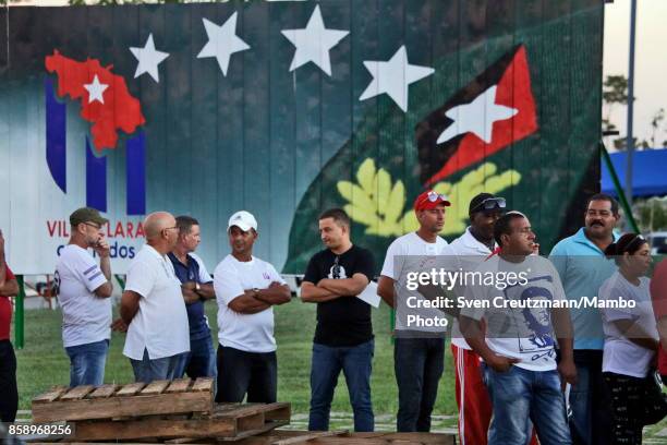 Cubans line up under an image that depicts Fidel Castros insignias prior to a political act at the Plaza de la Revolucion to celebrate the 50th...