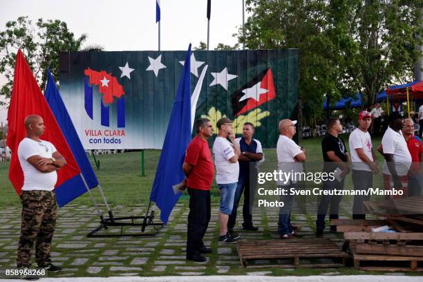 Cubans line up under an image that depicts Fidel Castros insignias prior to a political act at the Plaza de la Revolucion to celebrate the 50th...