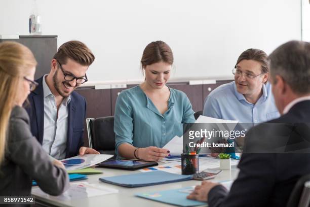 uomini d'affari sorridenti al tavolo delle riunioni - financial result foto e immagini stock