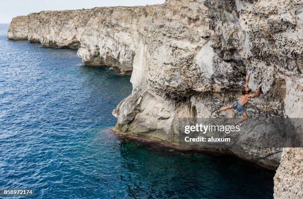 man practicing deep water soloing rock climbing in menorca spain - soloing stock pictures, royalty-free photos & images