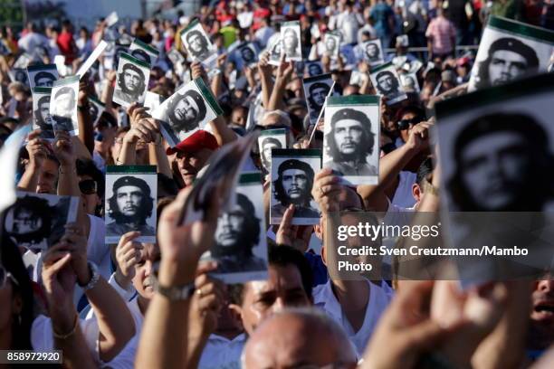 Cubans wave holding photos of Che Guevara during a political act at the Plaza de la Revolucion to celebrate the 50th anniversary of the death of...