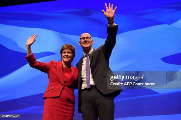 Scotland's First Minister Nicola Sturgeon waves on stage with the Deputy First Minister John Swinney on the opening day of the Scottish National...