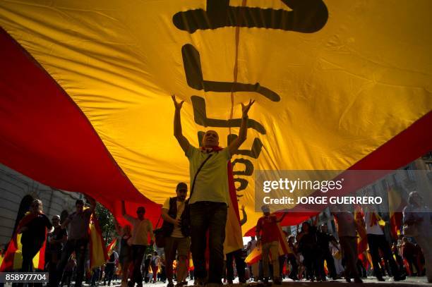 Protesters hols a giant Spanish flag during a demonstration called by "Societat Civil Catalana" to support the unity of Spain on October 8, 2017 in...