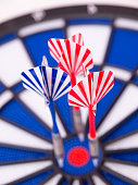 Dartboard with two red darts and one blue dart boked