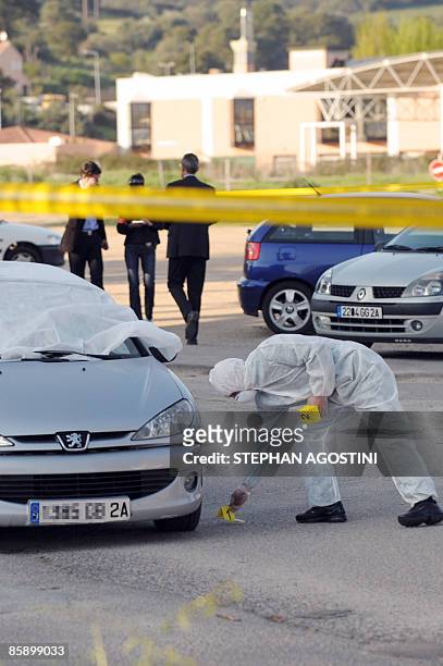 Des enquêteurs de la police judiciaire recherchent des indices, le 10 avril 2009 à Baléone dans la banlieue nord d'Ajaccio, autour d'une voiture ou...