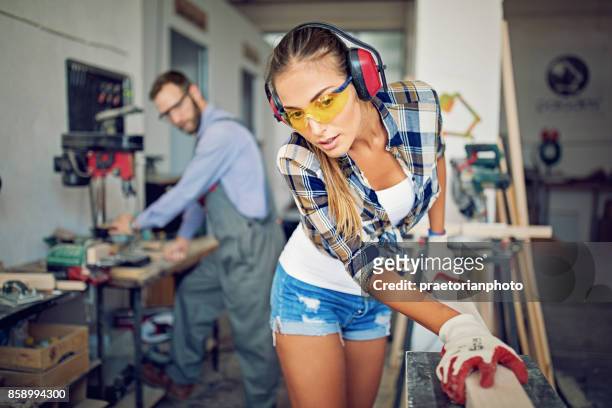 girl is working with machinery and timber in a small family carpenter factory - loud man imagens e fotografias de stock