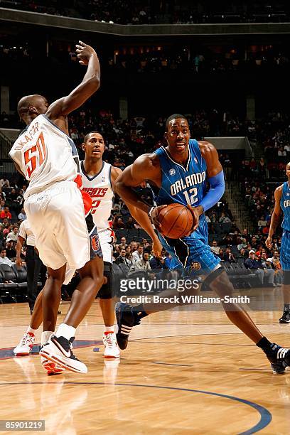 Dwight Howard of the Orlando Magic drives to the basket past Emeka Okafor and Boris Diaw of the Charlotte Bobcats during the game on February 20,...