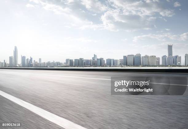 empty road with abu dhabi skyline - abu dhabi beach stock-fotos und bilder