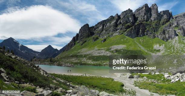 woman and two children walking in the water of alpine lake lago bianco, alpe veglia natural park - veglia stock-fotos und bilder