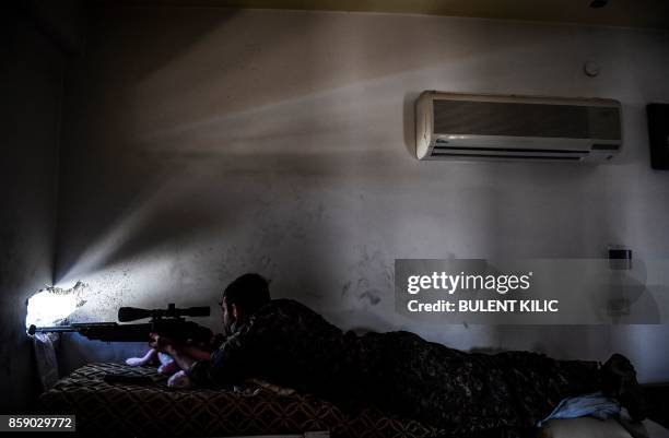 Member of the Syrian Democratic Forces , backed by US special forces, monitors Islamic State group positions on the western frontline in Raqa on...