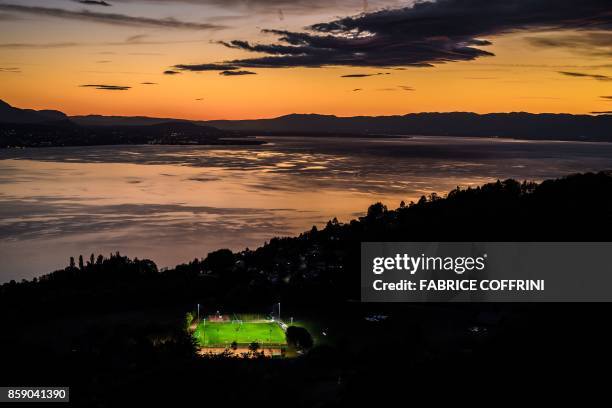 Picture taken on October 5 from the Mont de Gourze in Riez, western Switzerland, shows a football pitch illuminated with floodlights at sunset above...