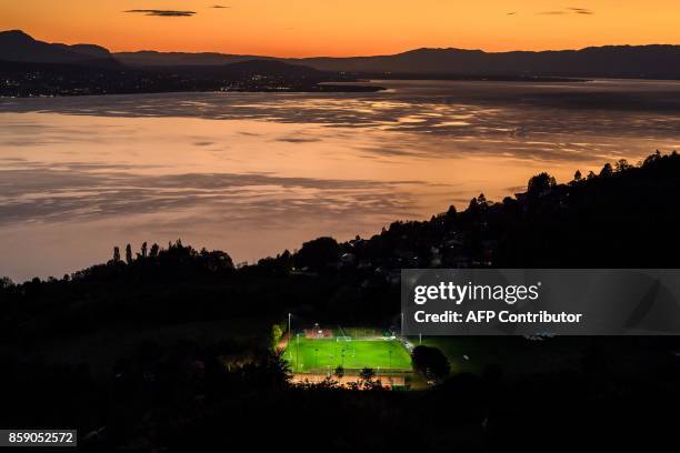 Picture taken on October 5 from the Mont de Gourze in Riez, western Switzerland, shows a football pitch illuminated with floodlights at sunset above...