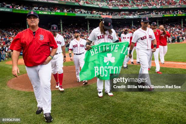 Hanley Ramirez of the Boston Red Sox carries a 'Believe In Boston' flag alongside manager John Farrell before game three of the American League...