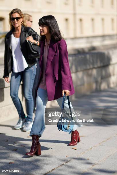 Guest wears a purple jacket, blue flare pants, brown boots, a blue bag, outside Nina Ricci, during Paris Fashion Week Womenswear Spring/Summer 2018,...