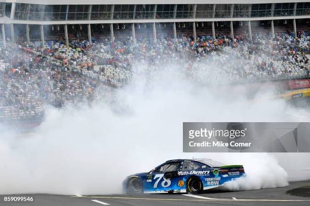 Martin Truex Jr, driver of the Auto-Owners Insurance Toyota, celebrates with a burnout after winning the Monster Energy NASCAR Cup Series Bank of...