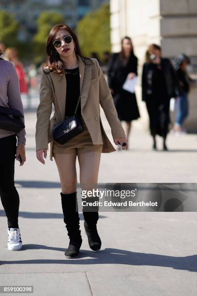 Guest wears a chanel bag, a beige blazer jacket, black boots, outside Nina Ricci, during Paris Fashion Week Womenswear Spring/Summer 2018, on...