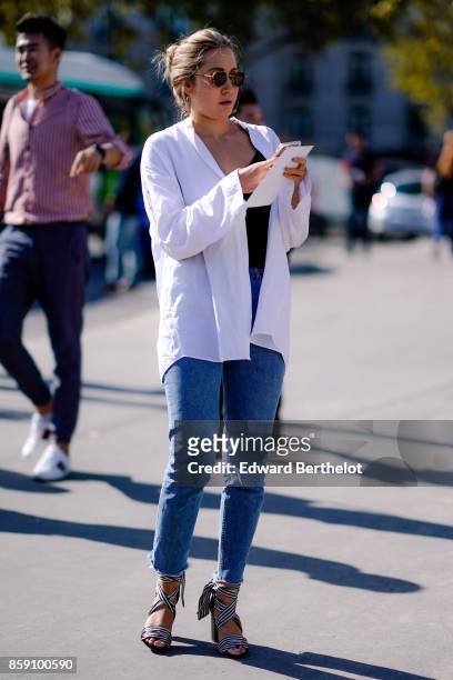 Guest wears a white open shirt, blue cropped pants, outside Nina Ricci, during Paris Fashion Week Womenswear Spring/Summer 2018, on September 29,...