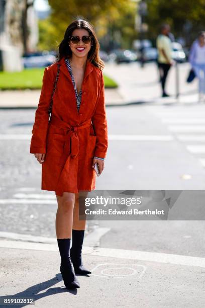 Guest wears a red coat, outside Nina Ricci, during Paris Fashion Week Womenswear Spring/Summer 2018, on September 29, 2017 in Paris, France.