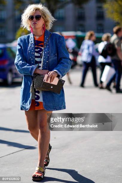 Guest wears a blue denim jacket, a dress, outside Nina Ricci, during Paris Fashion Week Womenswear Spring/Summer 2018, on September 29, 2017 in...
