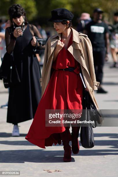 Guest wears a beige coat, a red dress, a beret hat, outside Nina Ricci, during Paris Fashion Week Womenswear Spring/Summer 2018, on September 29,...