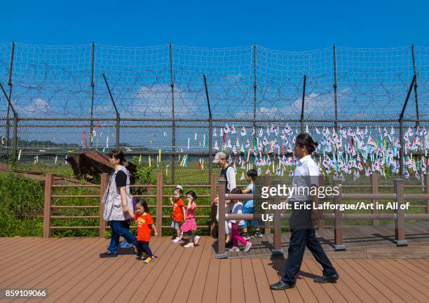 South Korean family passing in front of messages of peace and unity written on ribbons left on fence at DMZ, North Hwanghae Province, Panmunjom,...