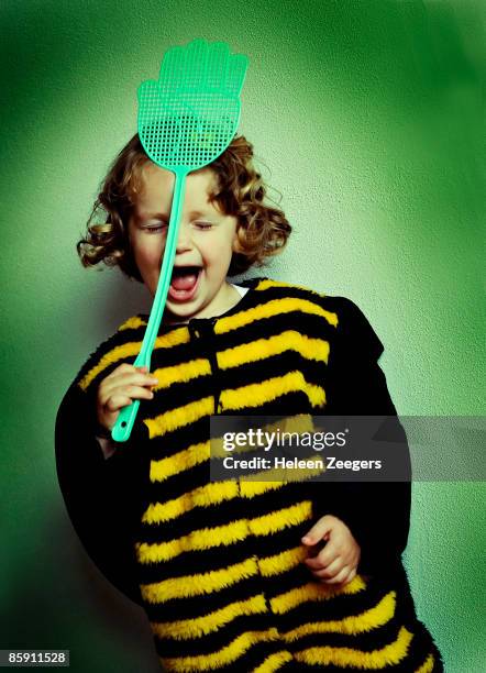 toddler dressed up as bee hitting self with swat - tierkostüm stock-fotos und bilder