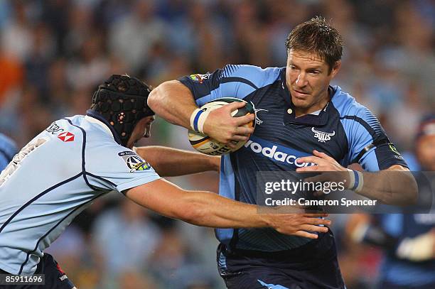 John Botha of the Bulls is tackled by Dean Mumm of the Waratahs during the round nine Super 14 match between the Waratahs and the Bulls at the Sydney...