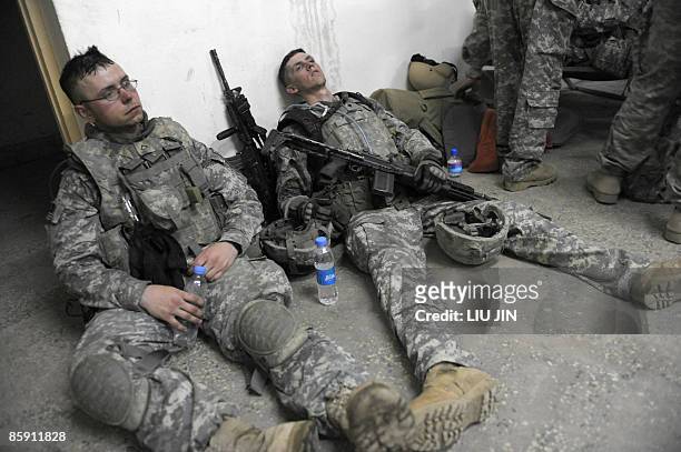 Two US soldiers from 1st Infantry Division lie exhausted on the floor at an operation post after completing a mission to search for weapons caches in...