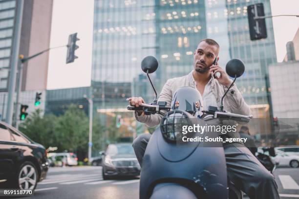 man on motor scooter using phone - riding vespa stock pictures, royalty-free photos & images
